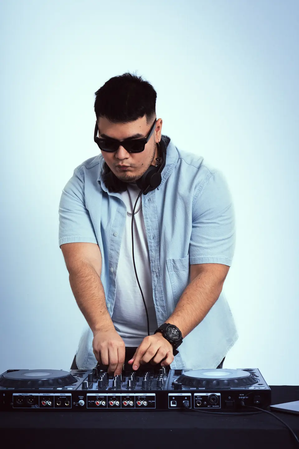 DJ Real mezclando, inclinado sobre la controladora