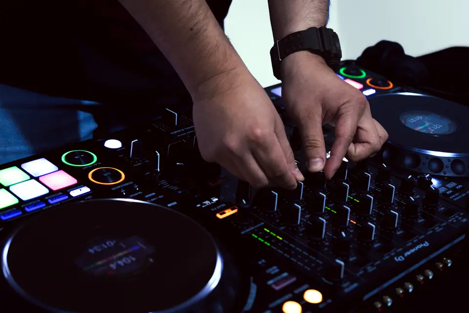 Manos de DJ Real sobre los platos y los pads iluminados